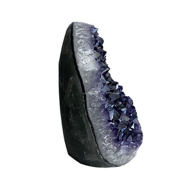 Side view of Brazilian amethyst geode showing protruding purple crystals, a pale mineral layer, and dark outer stone